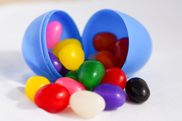 Colorful jelly beans spill out of a plastic Easter egg