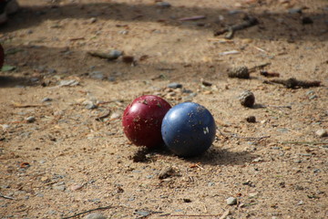 A red and blue bocce ball in the dirt
