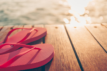 Flip flops at the wooden pier during sunset. Luxury vacation resort. Holiday getaway concept. Horizontal, warm toning