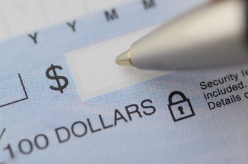 Close up of pen writing the dollar amount on a cheque with security features