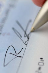 Vertical close up of pen signing a cheque with microprint security features