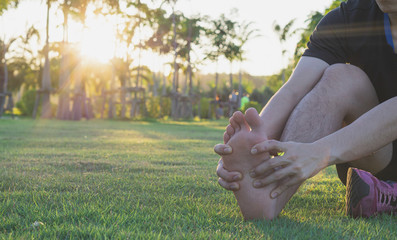 Young man massaging his painful foot from jogging and running on running track. Sport and exercise concept.