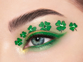 Conceptual photo of St. Patrick's Day. The eye of the young beautiful woman with bright green...