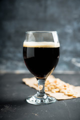 Freshly brewed dark beer on the black rustic background. Selective focus. Shallow depth of field.