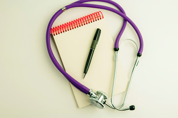 stethoscope notebook and pen on a white background