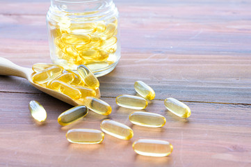 Pile of capsules Omega 3 in glass bottle on wood table