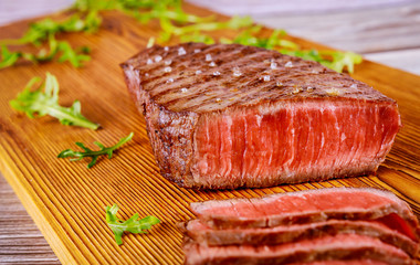 Grilled rare angus beef steak on wooden board.