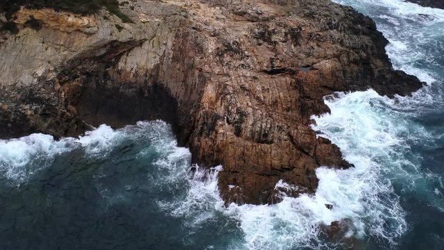 View of big waves breaking on the rocks of a little Island with percebes in a cloudy day. Finisterre.Spain. Drone Video
