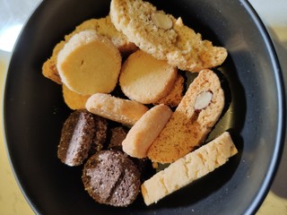 Round crackers of white and rye bread on a plate of dark color close-up.