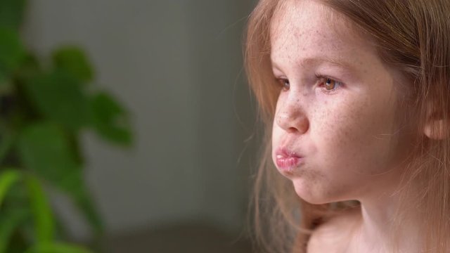 freckles little girl with eats a banana, side view