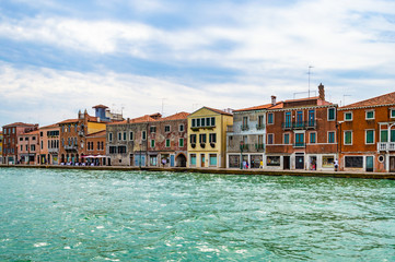 Fototapeta na wymiar Venice, Italy - CIRCA 2013: Colorful buildings of Venice at a cloudy summer afternoon; as seen from Venice Lagoon.