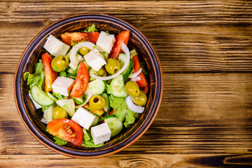 Ceramic plate with greek salad on wooden table. Top view