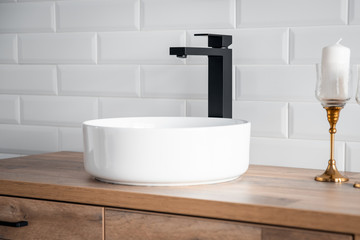 Black faucet for water and white separate high sink on wooden pedestal. Loft style bathroom