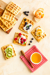 Belgian waffles with creamy cheese and berries on beige background top-down