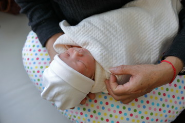 grandmother old hand holding cute baby newborn of grandchild with love