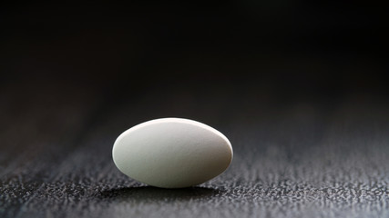 the white oval tablet is isolated on a black background.