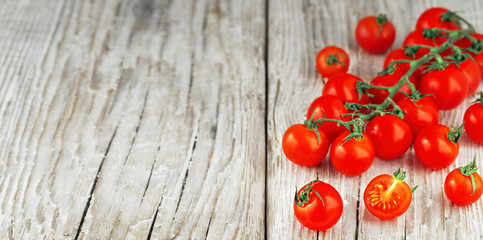 Fresh ripe cherry tomatoes on rustic wooden surface with natural light, close up, copy space for text.