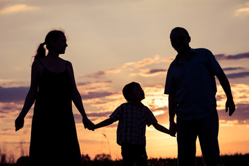 Fototapeta na wymiar Happy family standing in the park at the sunset time.