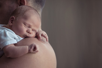 Father holding newborn baby son at the day time.