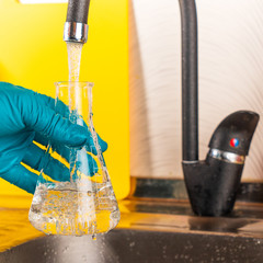 water purification specialist tap water pours into a glass flask.