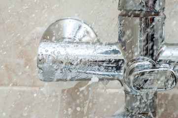 Water spray with shampoo on the background of the bathroom faucet