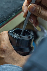 Technician hands holding tools and cleaning camera sensor