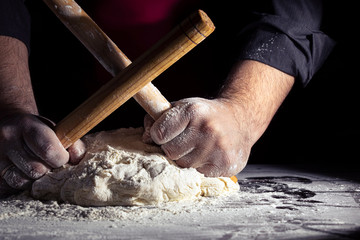 Chef hands cooking dough on dark wooden background. Food concept. Close-up