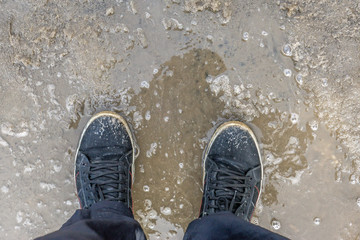 black sneakers mud bad weather, snow melts, puddles. coming of spring