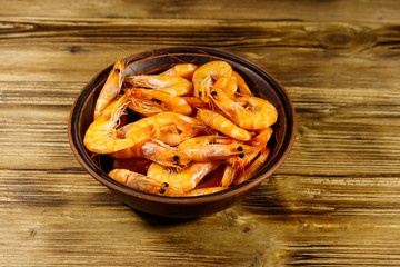 Fresh raw shrimps in a ceramic bowl on a wooden table