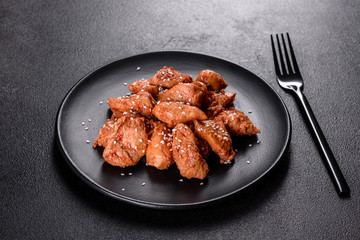Chicken fillet in sesame seeds, teriyaki sauce on a black stone plate