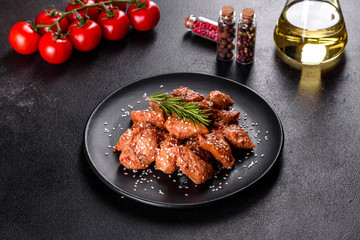 Chicken fillet in sesame seeds, teriyaki sauce on a black stone plate