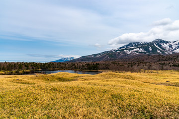 Obraz premium Beautiful lake and rolling mountain range on springtime sunny day. High latitude country natural beauty scenery. The First Lake of Shiretoko Goko Five Lakes, Shiretoko National Park. Hokkaido, Japan