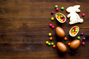 Easter sweets frame. Chocolate eggs and bunny gingerbread on dark wooden background top-down frame copy space