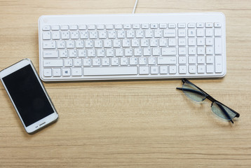 Flat lay white keyboard and other office supply on wooden table,with copy space.