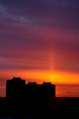 Fototapeta premium First sun lights. Orange, purple and yellow sky. Black house