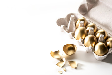 eggs painted with gold paint lie in a box on a white background.. space for text on the left