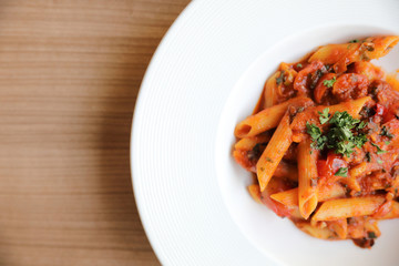 Penne arrabiata pasta tomato sauce with spices italian food on wood background