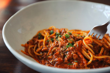 spaghetti Bolognese with minced beef and tomato sauce garnished with parmesan cheese and basil , Italian food