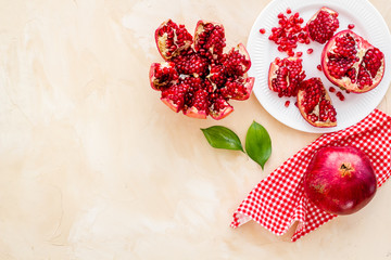 Juicy pomegranate with seeds on plate on beige table top-down copy space