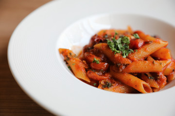 Penne arrabiata pasta tomato sauce with spices italian food on wood background