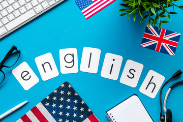 Obraz premium Learn English online. Concept with text, headset and keyboard on blue background top-down