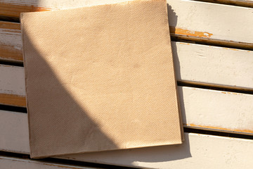 A recycled paper napkin lies on the cafe's light wooden table in the morning sun.