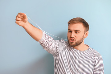 Funny man with chewing gum on color background