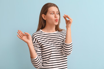 Funny young woman with chewing gum on light background