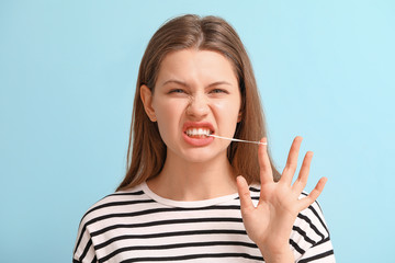 Funny young woman with chewing gum on color background