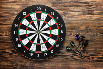 Darts with dartboard on wooden background