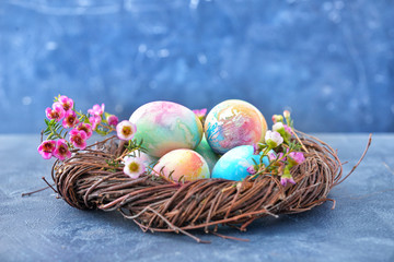 Nest with beautiful Easter eggs on color background