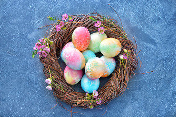 Nest with beautiful Easter eggs on color background