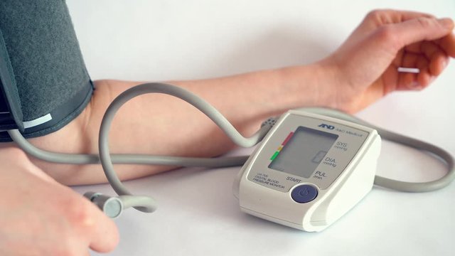 Measuring blood pressure with an electronic device at home in close-up.