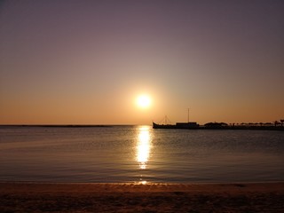 sunrise sunset on water background with reflection in the sea. shadows of beach houses and palm trees